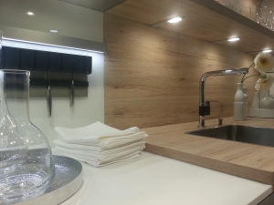 Weiße moderne Küche mit Holz-Arbeitsplatte und Nischenrückwand